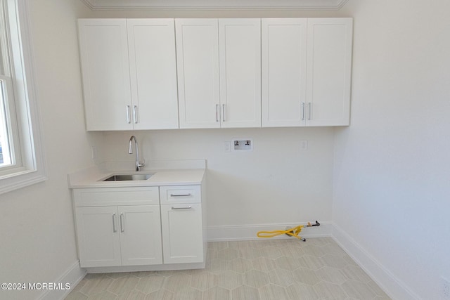 clothes washing area with cabinets, washer hookup, crown molding, and sink