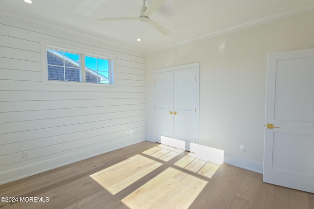 interior space featuring wood walls, ceiling fan, light hardwood / wood-style floors, and ornamental molding