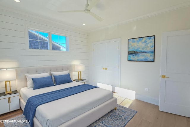 bedroom featuring light wood-type flooring, a closet, ceiling fan, and ornamental molding