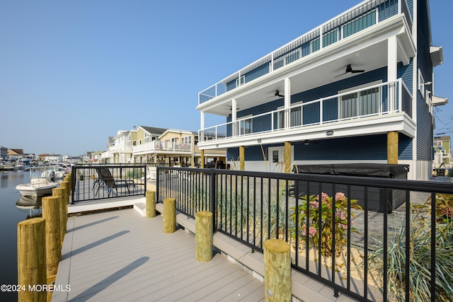 deck with ceiling fan and a water view