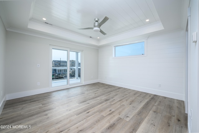 unfurnished room with a tray ceiling, ceiling fan, crown molding, and light wood-type flooring