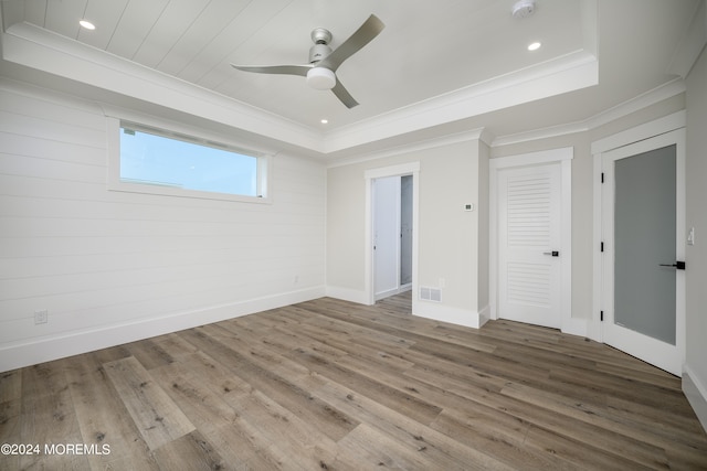 unfurnished bedroom featuring a tray ceiling, ceiling fan, wood-type flooring, and ornamental molding