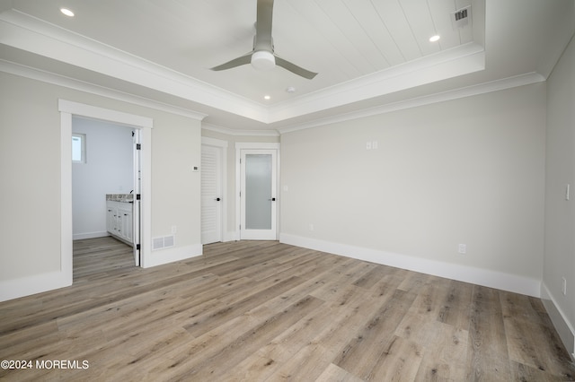 unfurnished bedroom featuring ceiling fan, a raised ceiling, light hardwood / wood-style flooring, ensuite bathroom, and ornamental molding