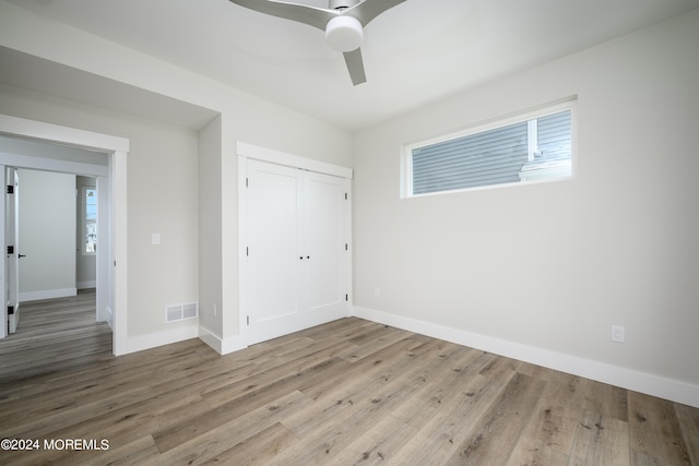 unfurnished bedroom featuring ceiling fan, light hardwood / wood-style floors, and a closet