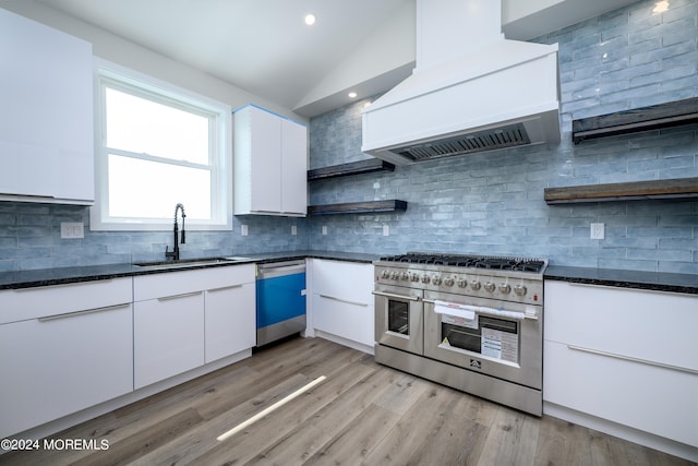 kitchen with white cabinetry, stainless steel appliances, light hardwood / wood-style floors, vaulted ceiling, and custom exhaust hood