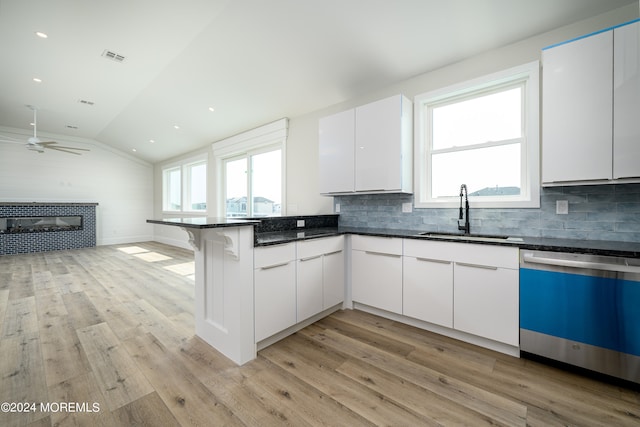 kitchen featuring dishwasher, white cabinetry, vaulted ceiling, and sink