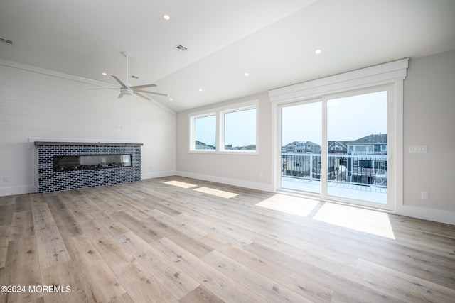 unfurnished living room featuring ceiling fan, lofted ceiling, a fireplace, and light hardwood / wood-style flooring