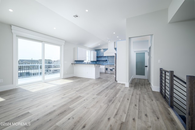 unfurnished living room featuring light hardwood / wood-style flooring and lofted ceiling