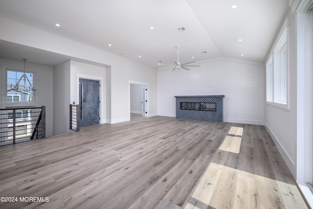 unfurnished living room featuring a fireplace, light wood-type flooring, vaulted ceiling, and ceiling fan