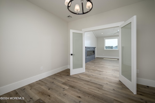 interior space with french doors, vaulted ceiling, an inviting chandelier, and light hardwood / wood-style flooring