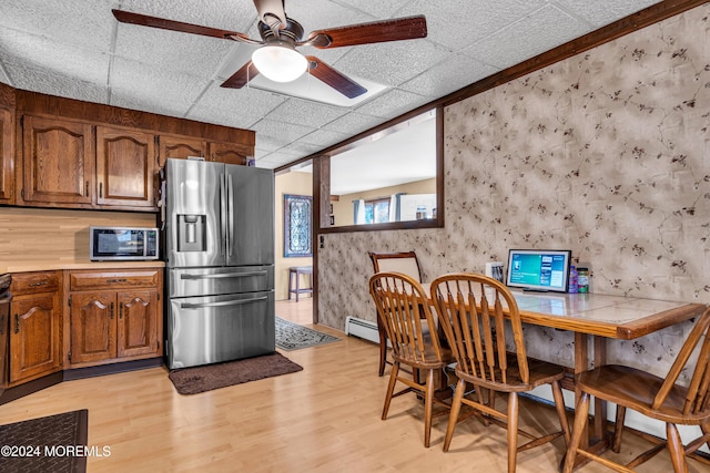 kitchen featuring a drop ceiling, stainless steel appliances, ceiling fan, a baseboard radiator, and light hardwood / wood-style flooring