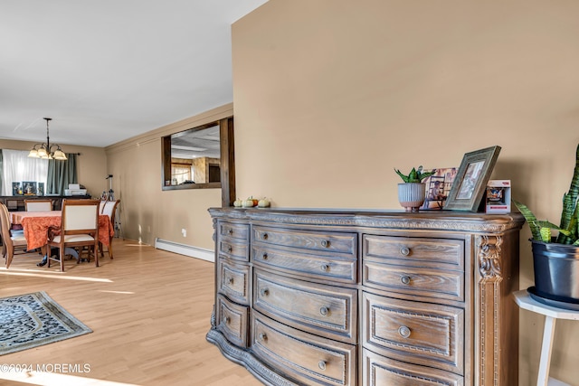 interior space featuring a chandelier, a baseboard heating unit, and light wood-type flooring