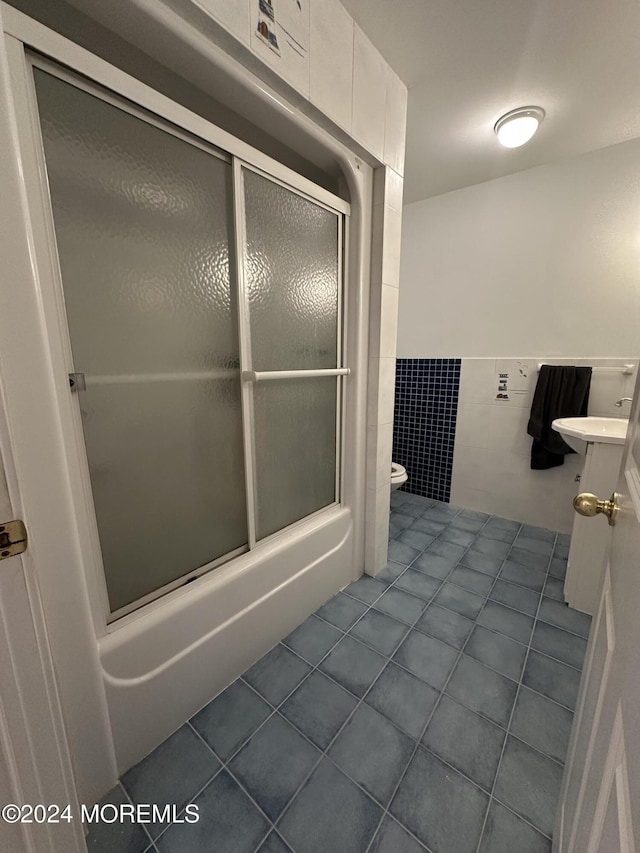 bathroom featuring tile patterned flooring, toilet, tile walls, and enclosed tub / shower combo