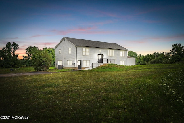 back house at dusk with a lawn