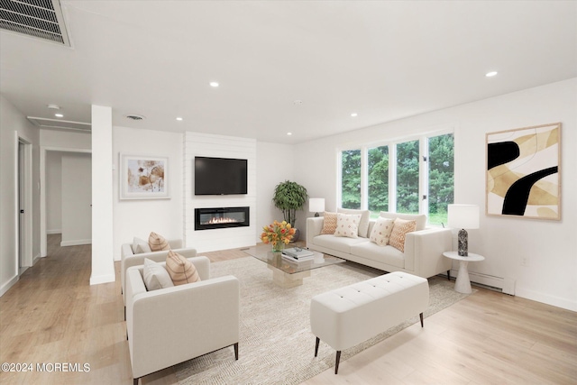 living room with a fireplace, a baseboard radiator, and light wood-type flooring