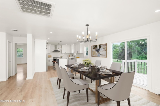 dining room with light wood-type flooring and an inviting chandelier