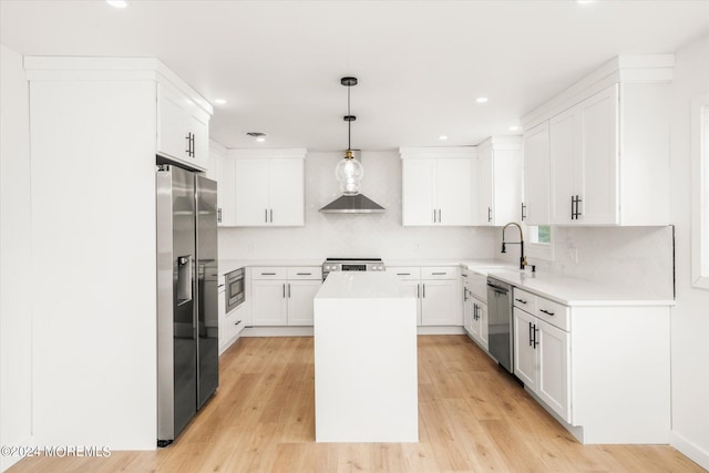 kitchen with pendant lighting, a kitchen island, stainless steel appliances, and light hardwood / wood-style flooring