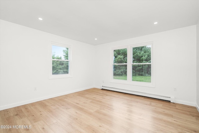 empty room featuring a healthy amount of sunlight, light hardwood / wood-style flooring, and a baseboard radiator