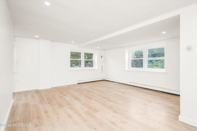 empty room featuring plenty of natural light, light wood-type flooring, and baseboard heating