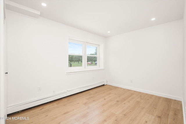 unfurnished room featuring a baseboard radiator and light wood-type flooring