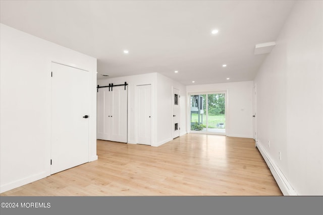 bonus room featuring a barn door, light hardwood / wood-style floors, and baseboard heating