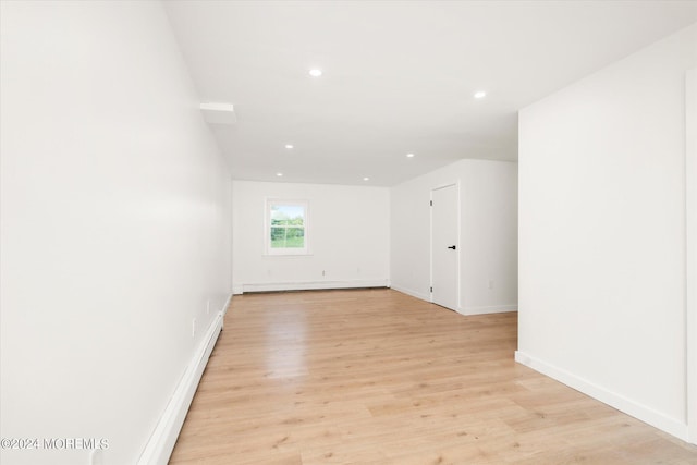 empty room with light hardwood / wood-style floors and a baseboard radiator