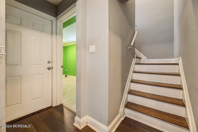 staircase with crown molding and wood-type flooring