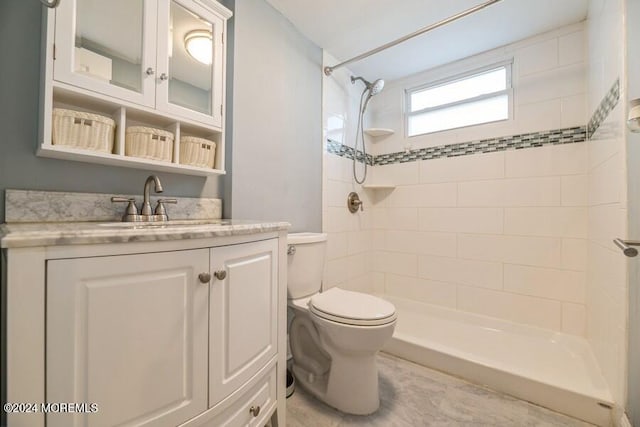 bathroom featuring toilet, vanity, and tiled shower