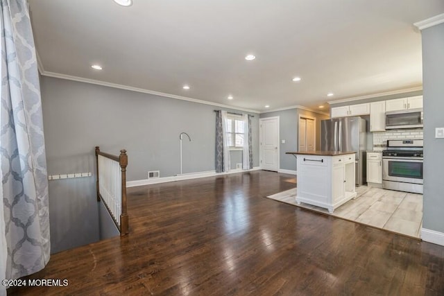 kitchen featuring appliances with stainless steel finishes, light wood-type flooring, white cabinetry, and crown molding