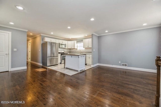 kitchen with appliances with stainless steel finishes, dark hardwood / wood-style flooring, white cabinets, a kitchen island, and a breakfast bar area