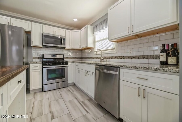 kitchen with dark stone countertops, white cabinetry, sink, and stainless steel appliances