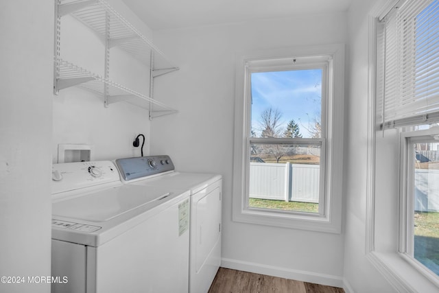 laundry area featuring washer and clothes dryer, plenty of natural light, and hardwood / wood-style flooring