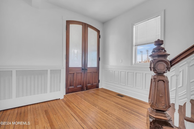 entrance foyer with french doors, light wood-type flooring, and radiator