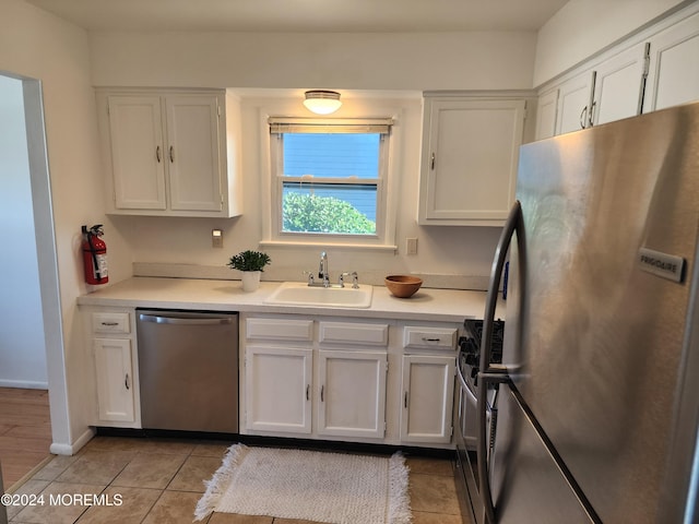 kitchen with white cabinets, light tile patterned floors, stainless steel appliances, and sink