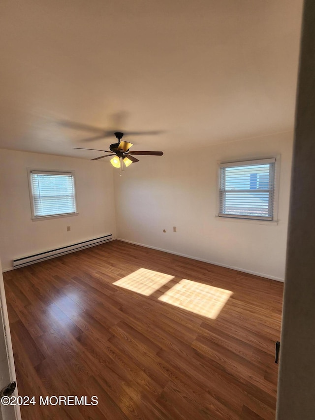 unfurnished room with ceiling fan, dark hardwood / wood-style flooring, and a baseboard heating unit