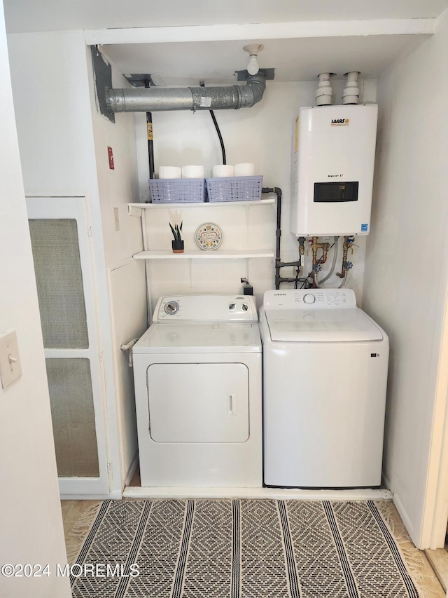 washroom with washing machine and clothes dryer and water heater