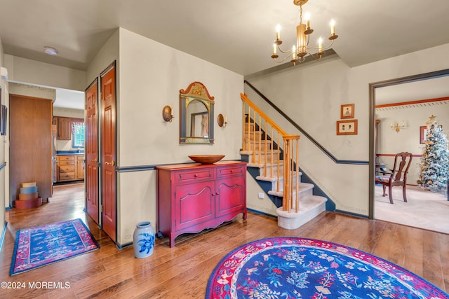 stairway with wood-type flooring and an inviting chandelier