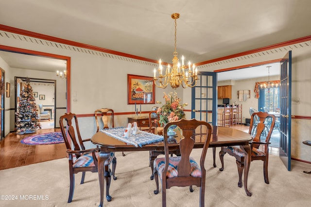 dining area with french doors, light hardwood / wood-style floors, and an inviting chandelier