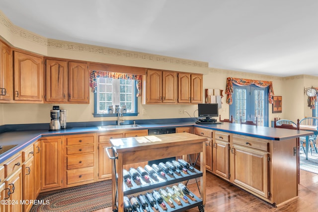 kitchen with hardwood / wood-style floors, dishwasher, a kitchen island, and sink