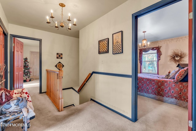 corridor featuring light carpet and a chandelier