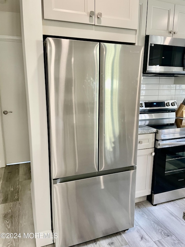 kitchen featuring decorative backsplash, white cabinetry, light hardwood / wood-style flooring, and stainless steel appliances