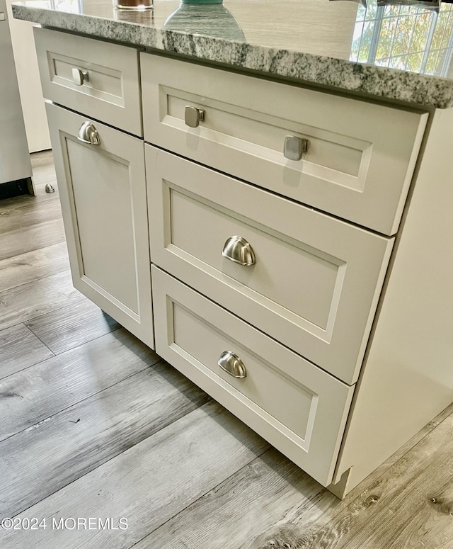 interior details featuring light stone counters, light hardwood / wood-style floors, and stainless steel dishwasher