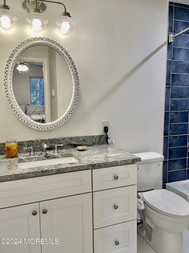 bathroom with tile patterned flooring, vanity, toilet, and ceiling fan