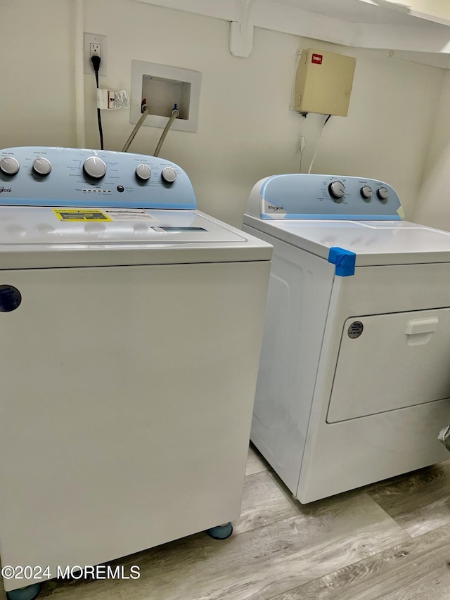 washroom with washing machine and dryer and light hardwood / wood-style flooring