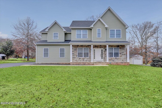 front of property with a front yard, a porch, a garage, and an outdoor structure