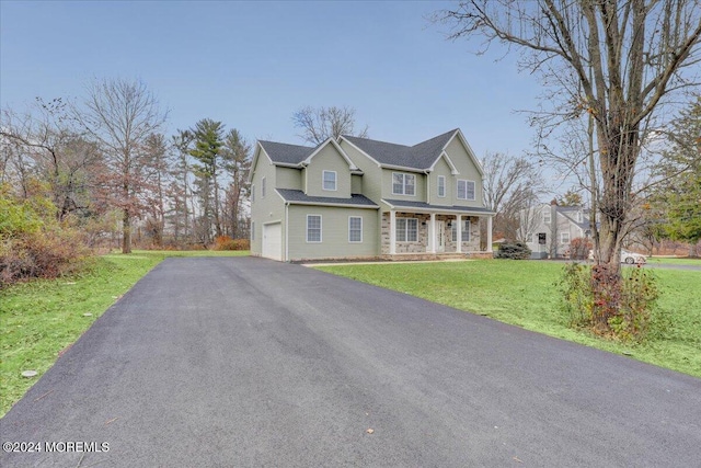 view of front of home featuring covered porch, a front yard, and a garage