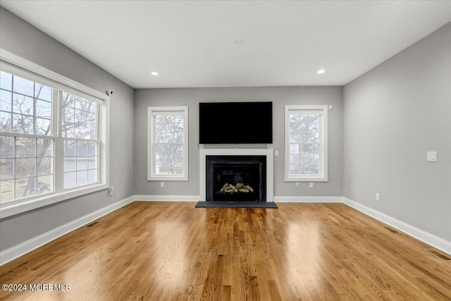 unfurnished living room featuring a healthy amount of sunlight and light hardwood / wood-style floors