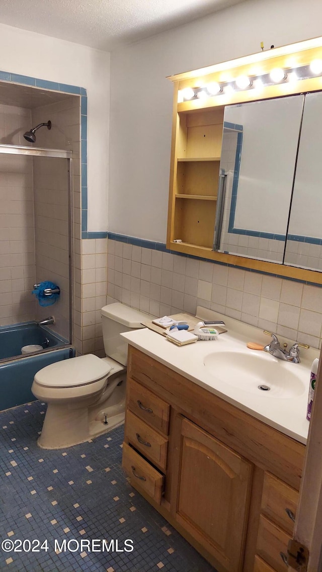 full bathroom with vanity, tile patterned floors, toilet, tile walls, and a textured ceiling