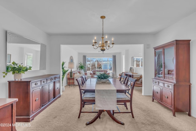 carpeted dining room featuring a notable chandelier