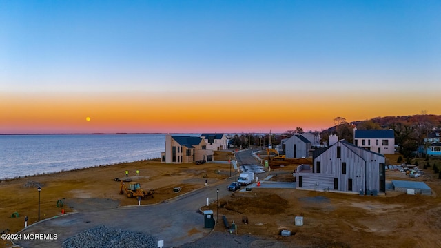 aerial view at dusk with a beach view and a water view